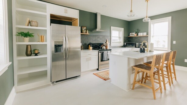 A modern kitchen with white cabinetry, a stainless steel refrigerator, and a central island with bar stools. - Newly Renovated, Vintage Inspired, Large 4 BR Home (Mount Joy)