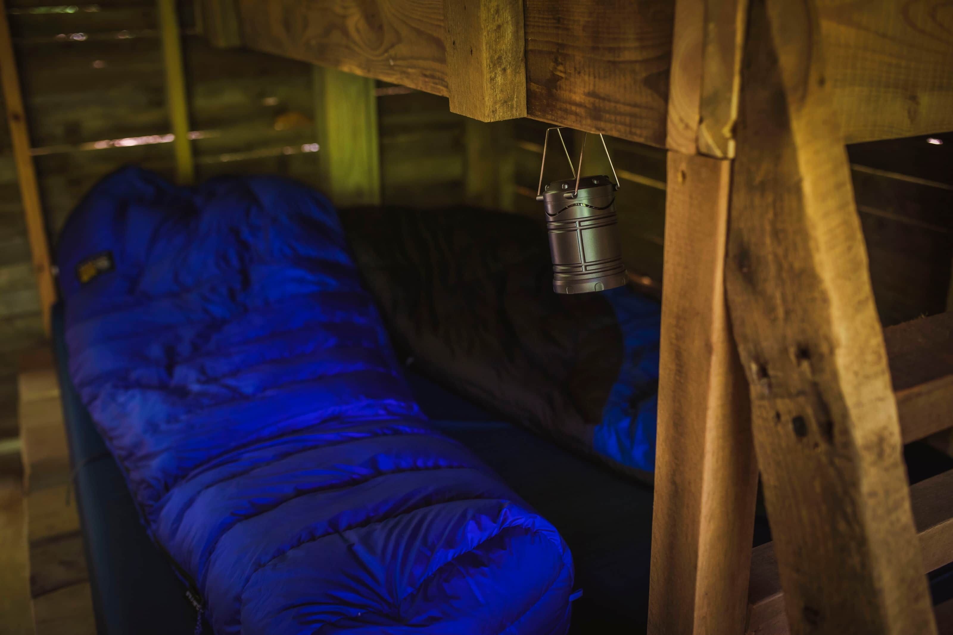 A wooden bed frame with a metal lantern hanging above it.