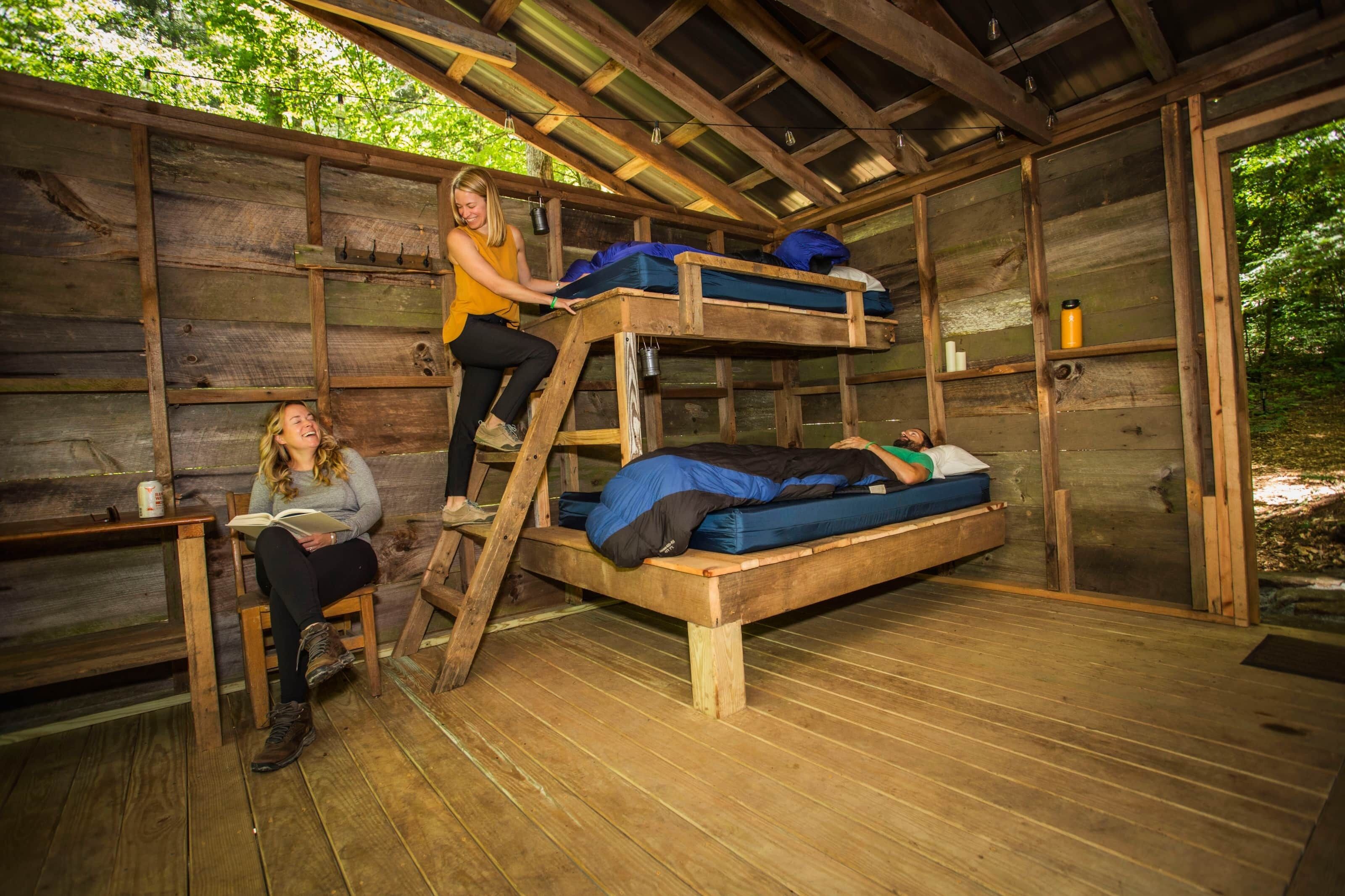 A rustic cabin with a wooden interior, a bunk bed, and a ladder.