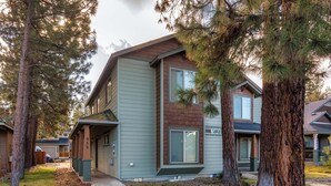 A two-story building with a visible garage door, a front porch, and a well-maintained lawn.