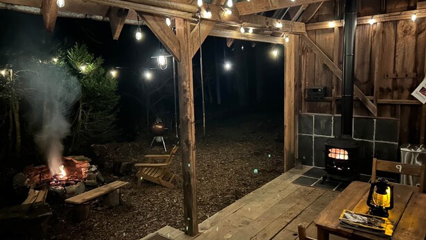 An outdoor wooden deck with a barbecue grill, a stone fireplace, and string lights. - Bill's Cabin - 38 acres- hiking, mountain biking, waterfall (Zirconia)