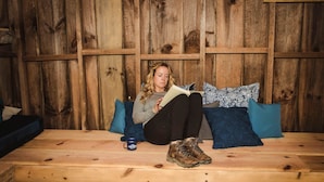 A person sitting on a wooden bench with a book and a mug, against a wooden wall. - Bill's Cabin - 38 acres- hiking, mountain biking, waterfall (Zirconia)