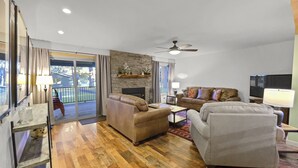 A spacious living room with a fireplace, leather sofas, wooden flooring, and a balcony with a view. - Walk to Sisters | Hot Tub, Pool + Fireplace (Sisters)