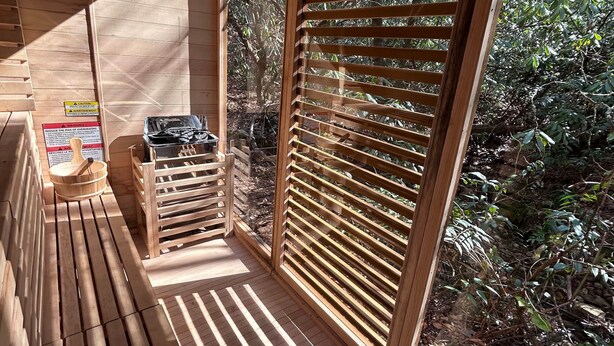 Une terrasse en bois offrant une vue sur le feuillage, un panneau d’avertissement et une boîte à outils.