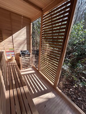 Une terrasse en bois offrant une vue sur le feuillage, un panneau d’avertissement et une boîte à outils.