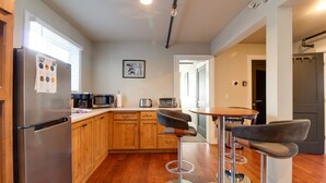 Una cocina moderna con gabinetes de madera, electrodomésticos de acero inoxidable y una zona de bar con taburetes.