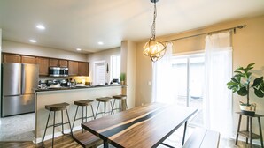 Una cocina moderna con electrodomésticos de acero inoxidable, una isla de madera con taburetes altos y un amplio comedor.