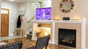 Una sala de estar con chimenea, televisor y escalera.