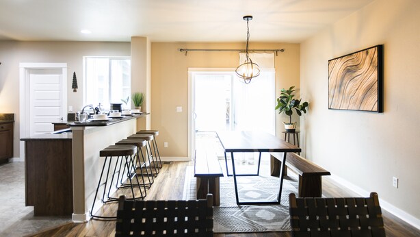 Una cocina moderna con barra, suelo de madera y una mesa de comedor con sillas.