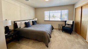 A bedroom with a bed, bedside tables, a chair, a window, and a ceiling light.