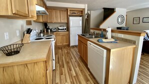 A compact kitchen with wooden cabinets, a built-in stove, a sink, and a dishwasher.