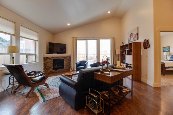 A spacious living room with a fireplace, comfortable seating, a television, and a bookshelf. - The Quails Nest - charming 3 bedroom 2.5 bath with fireplace in Sisters Oregon (Sisters)