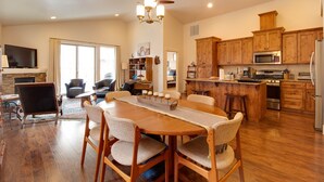 A spacious kitchen with wooden cabinets, a dining area with a long table and chairs, and a television mounted on the wall. - The Quails Nest - charming 3 bedroom 2.5 bath with fireplace in Sisters Oregon (Sisters)