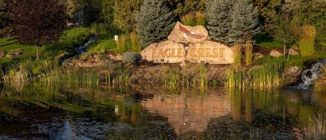 A pond with a rock inscribed with "EAGLE CREST" surrounded by greenery and trees.