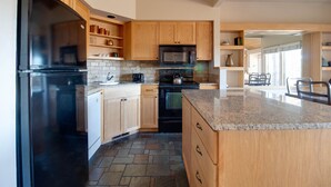 Una cocina moderna con armarios de madera, un refrigerador negro, un microondas y una encimera de granito.