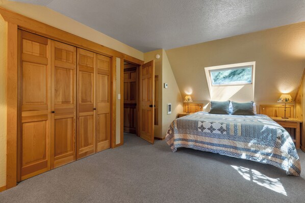 A bedroom with a large bed, wooden wardrobe, and a window with a view.