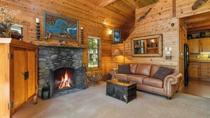 L’intérieur d’un chalet chaleureux, avec une cheminée en pierre, un canapé en cuir et des murs en bois.