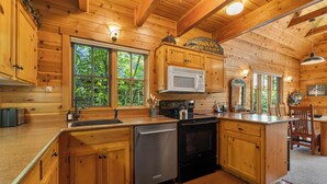 Une cuisine rustique, située dans une cabane en bois, équipée d’un lave-vaisselle, d’une cuisinière et d’un four à micro-ondes.