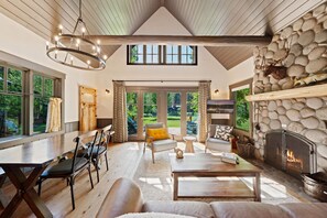 Un salón espacioso con chimenea de piedra, ventanas amplias y techo alto.