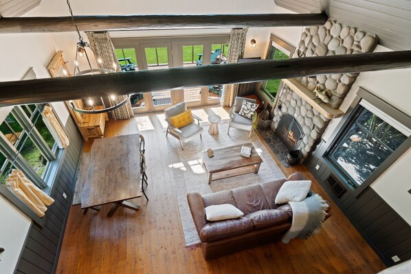 Amplia sala de estar con chimenea, muebles de madera y grandes ventanas con vistas a un jardín.