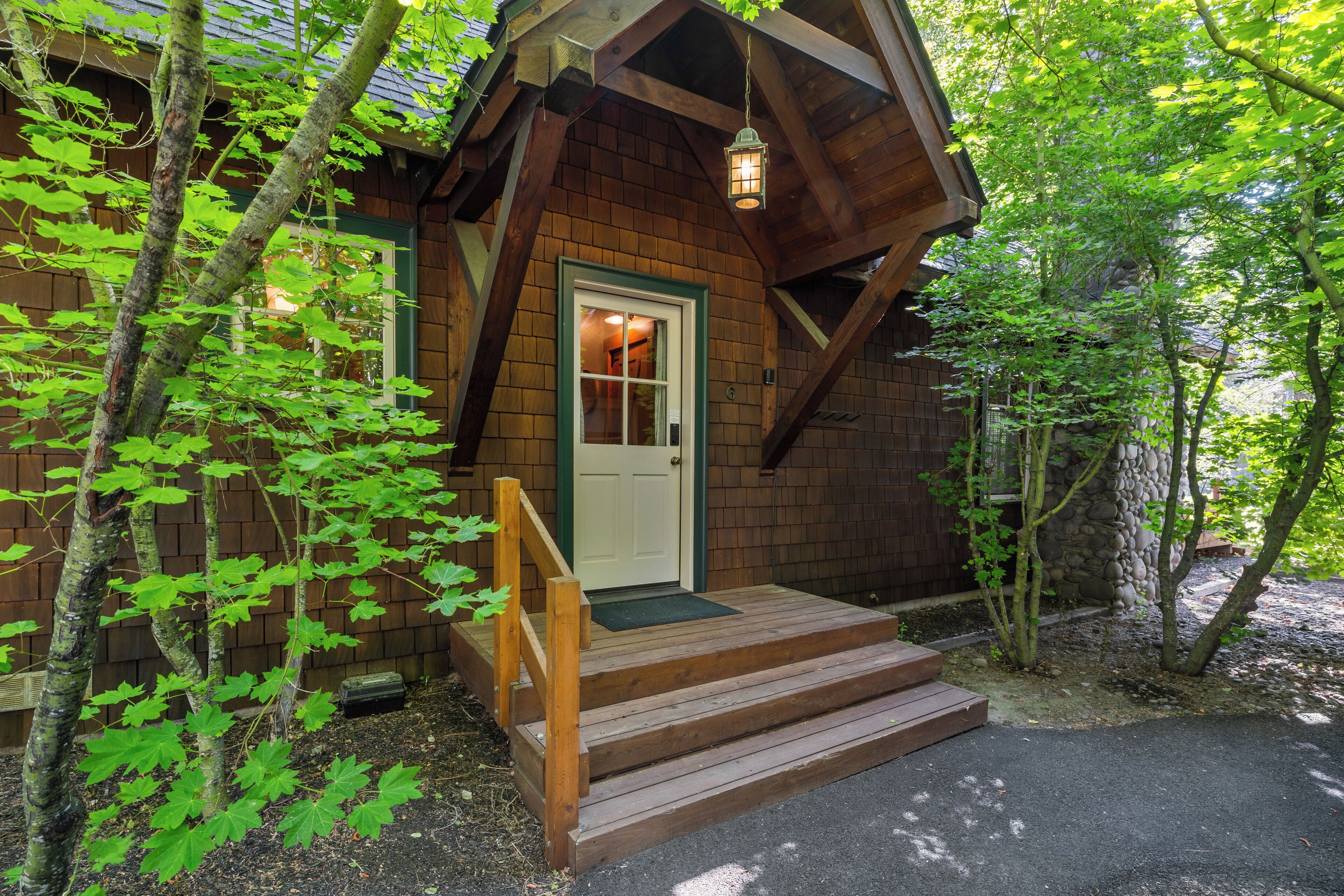 Une cabane en bois avec une porte d’entrée, un escalier en bois et une véranda.