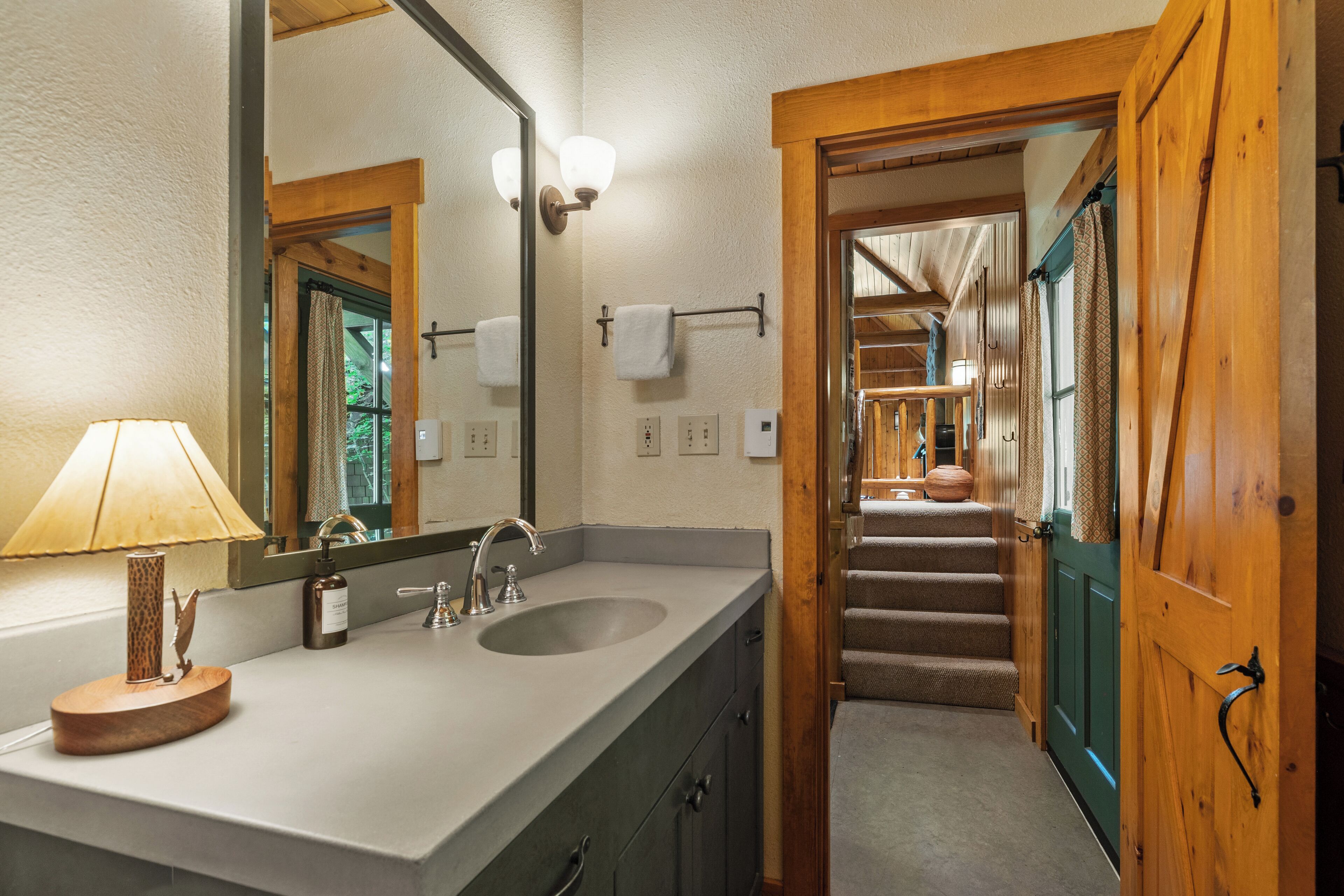 Une salle de bain avec une porte en bois, un lavabo avec un miroir et un porte-serviettes.