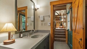 A bathroom with a wooden door, a sink with a mirror, and a towel rack.