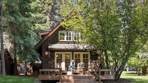 Un chalet rustique doté d’une terrasse en bois, de grandes fenêtres et d’un porche.