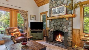 A cozy living room with a stone fireplace, leather furniture, and a television.