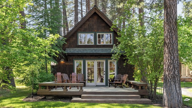 A cabin with a porch, two windows, and a door.
