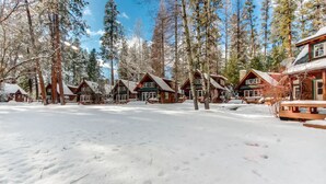 A row of log cabins in a snowy forest setting.