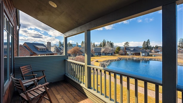 A covered porch with a view of a lake and houses in the background. - Mountain Views | Pond Views | Cozy Fireplace (Sisters)
