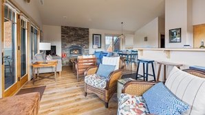 A spacious living area with a fireplace, wicker furniture, and a dining area with stools. - Mountain Views | Pond Views | Cozy Fireplace (Sisters)