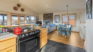 A modern kitchen with a stove, dining area with chairs, and a fireplace. - Mountain Views | Pond Views | Cozy Fireplace (Sisters)