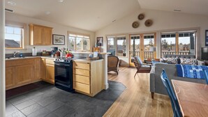 A spacious kitchen with wooden cabinets, a large island, and a dining area with a table and chairs. - Mountain Views | Pond Views | Cozy Fireplace (Sisters)
