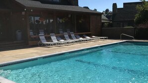 Une piscine rectangulaire à l’eau d’un bleu limpide, entourée d’une terrasse carrelée. Des chaises longues sont alignées le long du bord de la piscine.