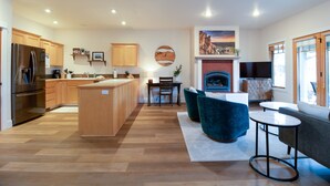 Una cocina moderna con armarios de madera, una isla central y una zona de comedor con una silla azul y una mesita.