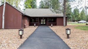 A building with a covered entrance, a paved walkway leading to it, and two lantern-style lights on either side. - Cozy Tollgate Cabin Near Trails + Pool (Sisters)