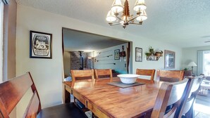 A dining area with a wooden table and chairs, a chandelier, and framed pictures on the walls. - Cozy Tollgate Cabin Near Trails + Pool (Sisters)