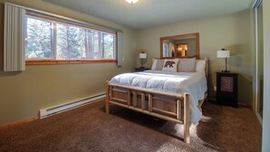 A bedroom with a wooden bed, a window, a mirror, and a nightstand with a lamp. - Cozy Tollgate Cabin Near Trails + Pool (Sisters)