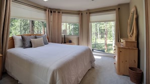 A bedroom with a large bed, a wooden dresser, and a skylight.