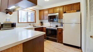 A kitchen with wooden cabinets, a microwave, an oven, and a refrigerator. - Fourth Sister Getaway Condo 2 bdrm 2 bth sleeps 6, fireplace, community pool/spa (Sisters)