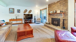 A living room with a stone fireplace, a television, a sofa, and a red leather chair. - Fourth Sister Getaway Condo 2 bdrm 2 bth sleeps 6, fireplace, community pool/spa (Sisters)