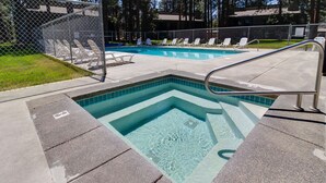 A swimming pool with a small hot tub, surrounded by lounge chairs and a fenced area. - Fourth Sister Getaway Condo 2 bdrm 2 bth sleeps 6, fireplace, community pool/spa (Sisters)
