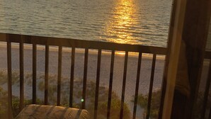 En balkon med udsigt til solnedgangen over havet.