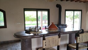 A bar area with a tiled floor, woven chairs, a central bar counter, and a thatched ceiling. - Maison Avec Piscine Privée, Jardin Arboré, Parking Clos à 2 kms D'amizmiz (Amizmiz)