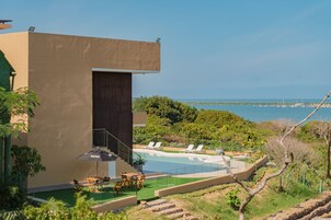 Un edificio moderno con piscina, sillas de descanso y vistas al mar.