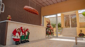 Uma área de recepção com piso estampado, um pinheiro de Natal e três ursinhos de pelúcia vestidos para a ocasião.