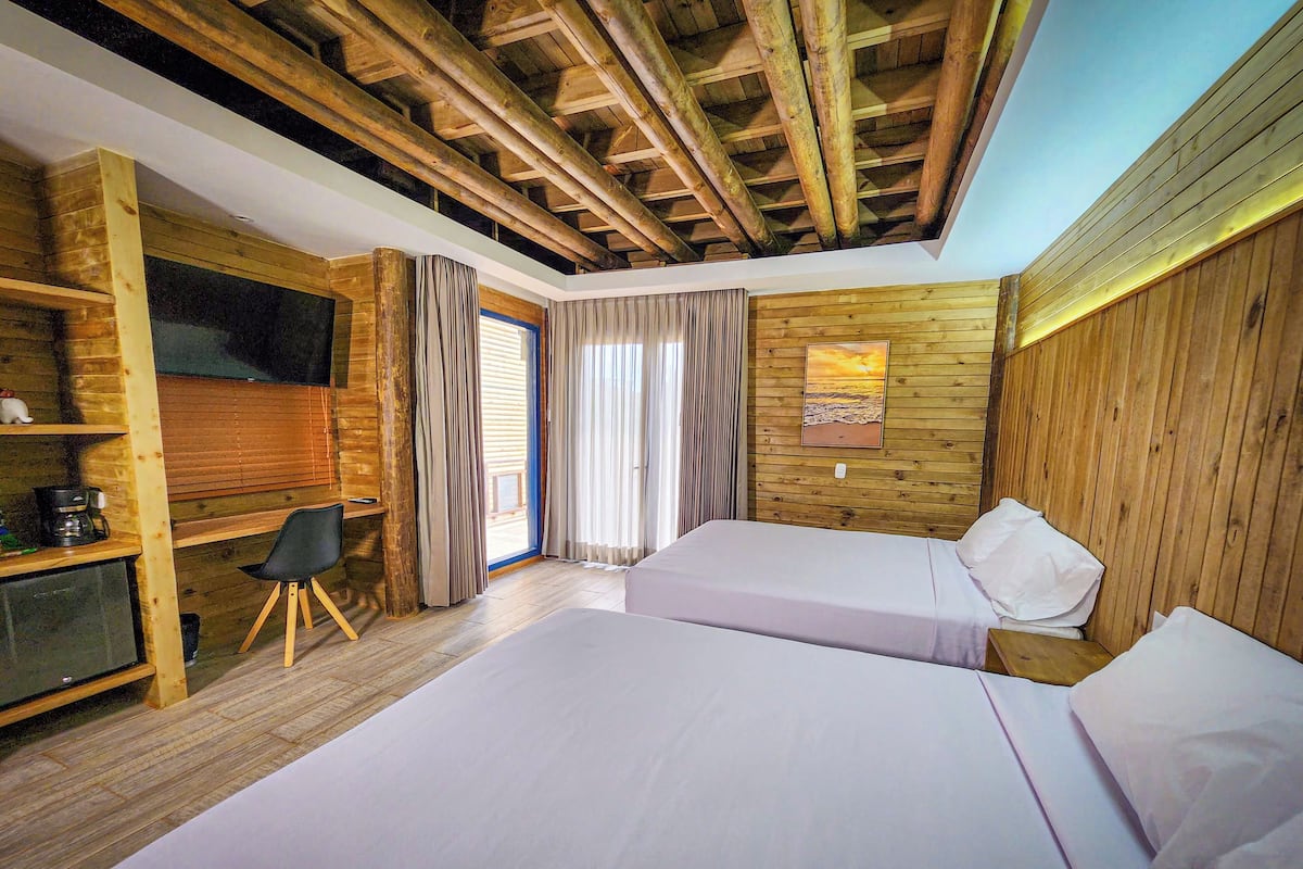 A room with wooden walls, a bed, a desk, and a TV.