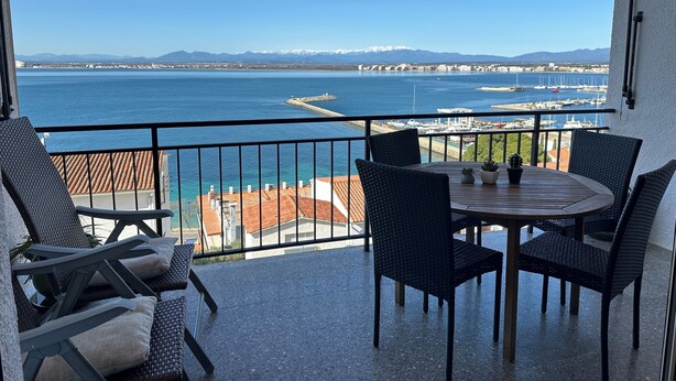 Un balcon avec vue sur la mer, une table avec des chaises et une rambarde.